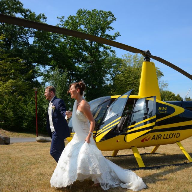 Ein Brautpaar läuft an einem Gelben AirLloyd Helikopter vorbei