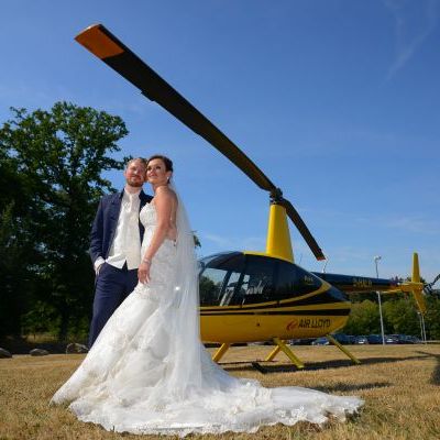 Ein Brautpaar steht vor einem gelben Helikopter