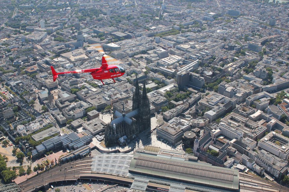 Red helicopter makes a sightseeing flight over Cologne Cathedral.