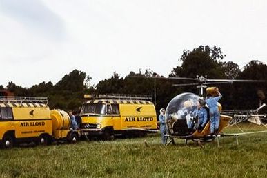 Ein Hubschrauber und zwei Air Lloyd Fahrzeuge auf einer Wiese